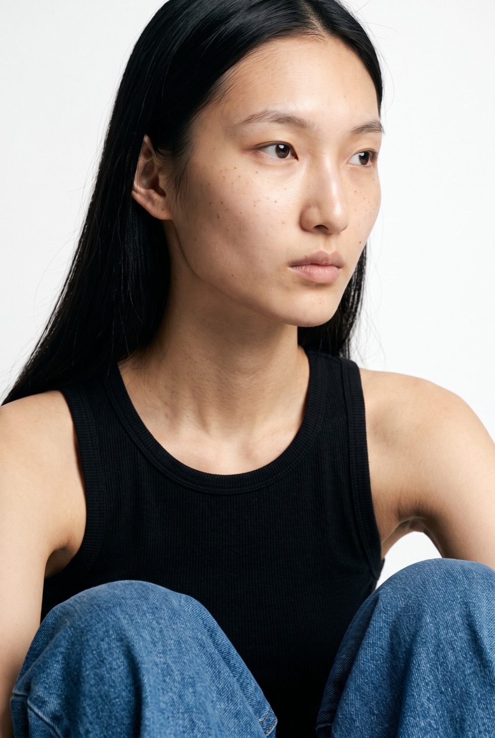 Synthetic talent, long dark hair, seated — not a real person